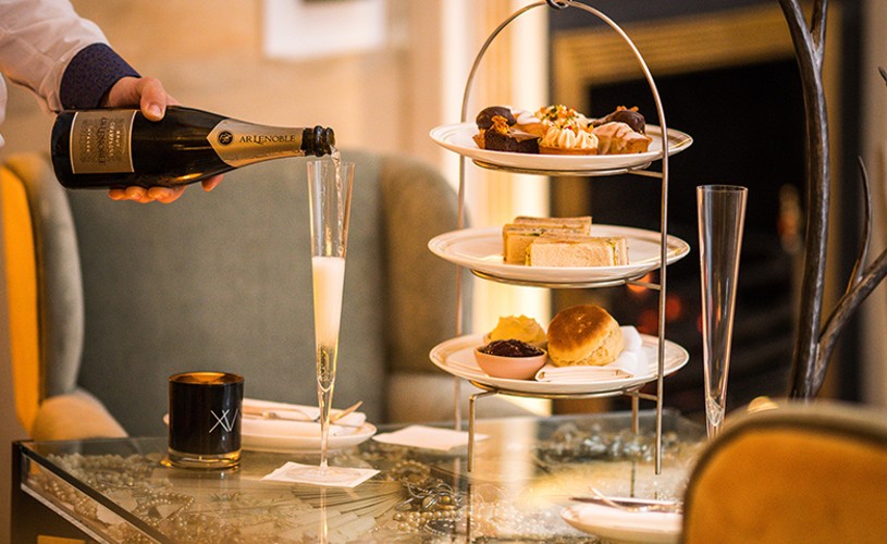 Person serving champagne next to afternoon tea at No.15 Great Pulteney